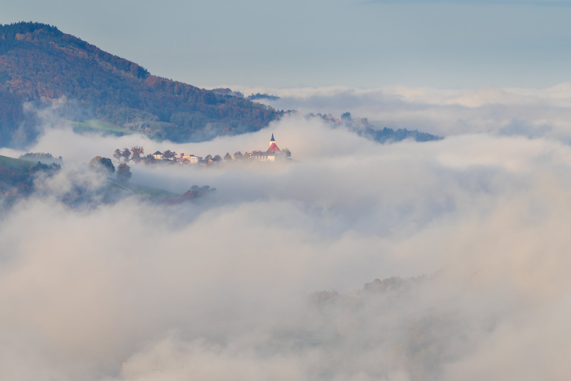 Small village St. Michael am Bruckbach residing high above the thick autumn fog, Austria